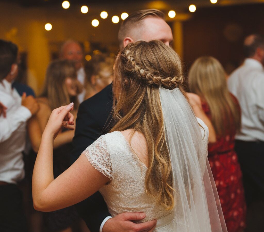 Bride dancing at her reception with an intact braided half-up hairstyle