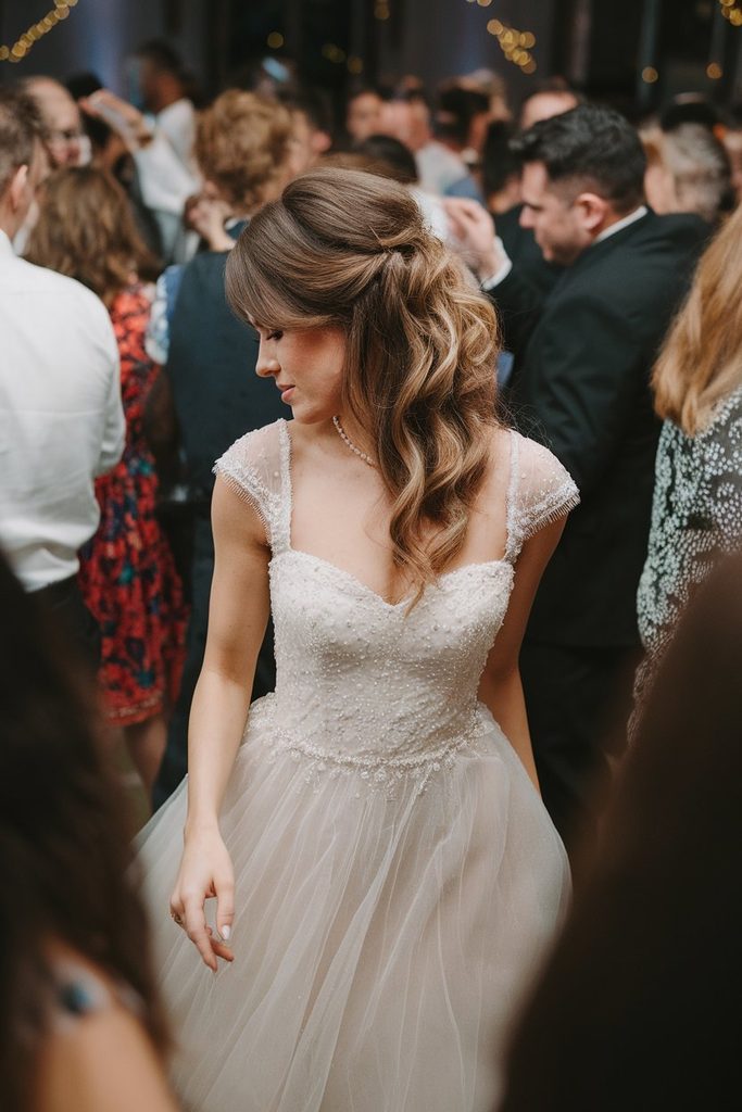 Bride on a crowded dance floor with her half-up hairstyle holding up