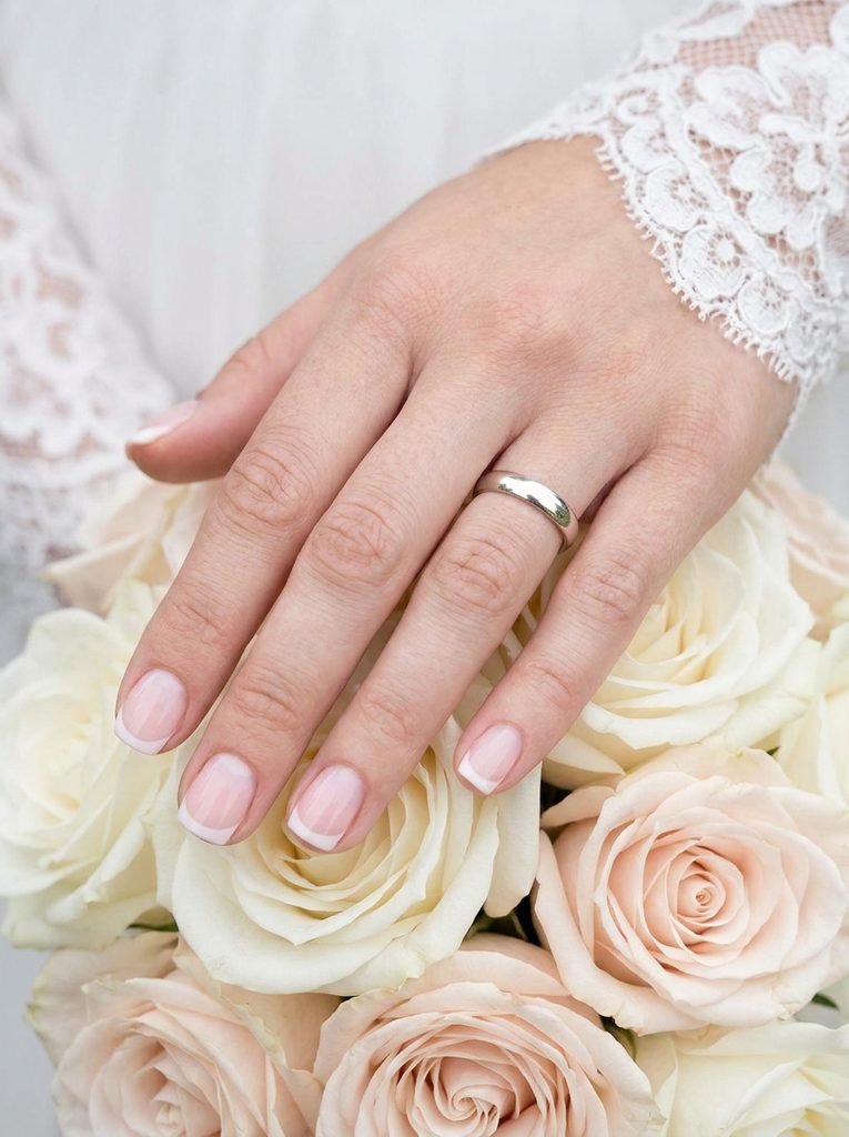 Bride's hand with a soft French tip manicure on short nails