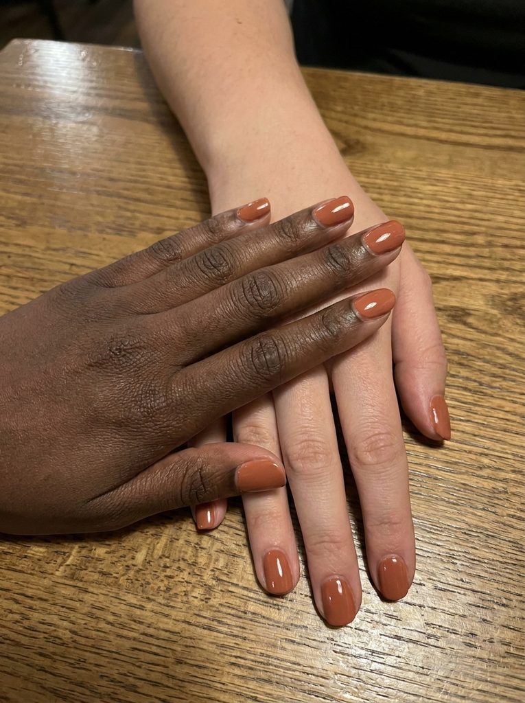 Close-up of hands with different skin tones wearing the same nail polish shade