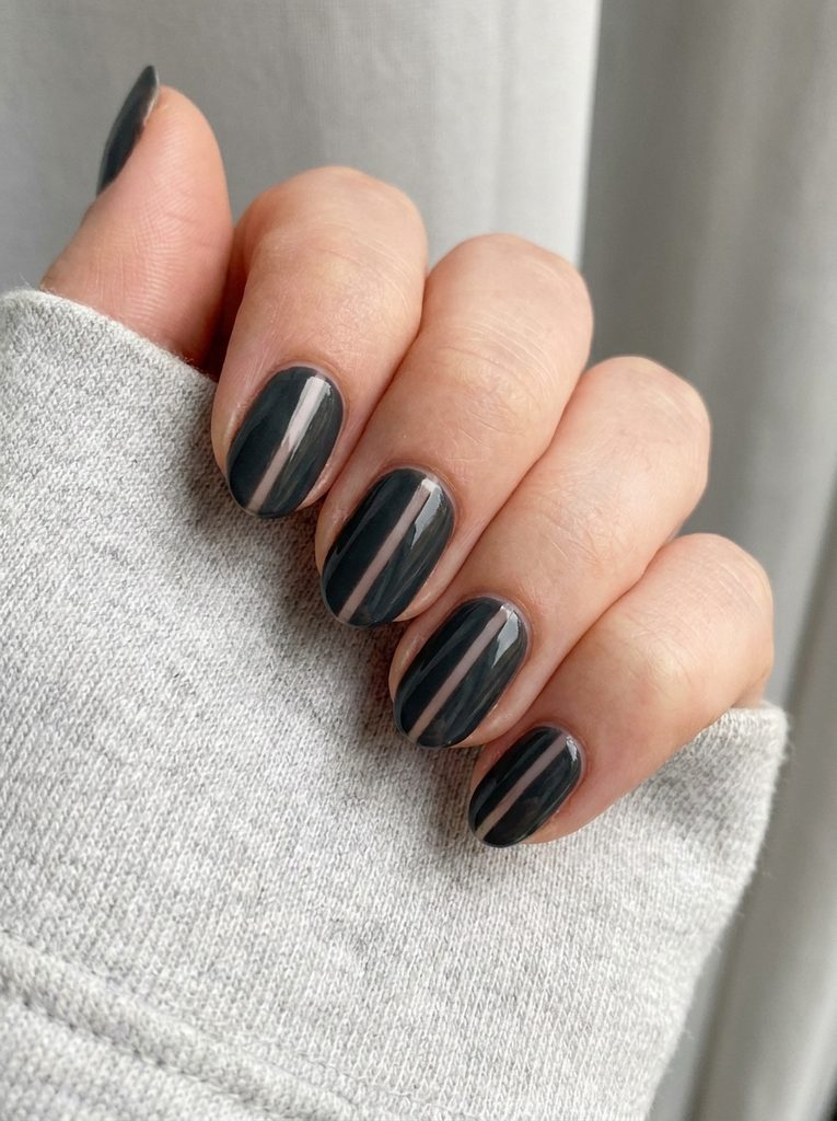 Hand with a negative space nail design featuring a thin unpainted line