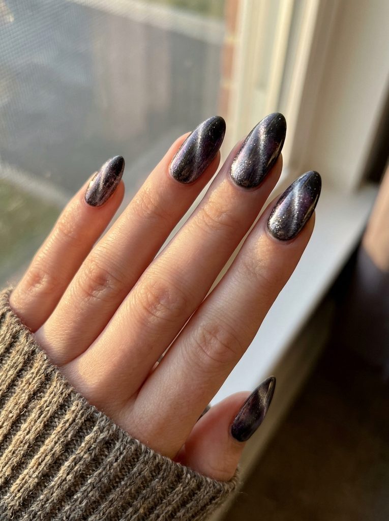 Nails with a shimmering cat-eye polish finish catching soft light