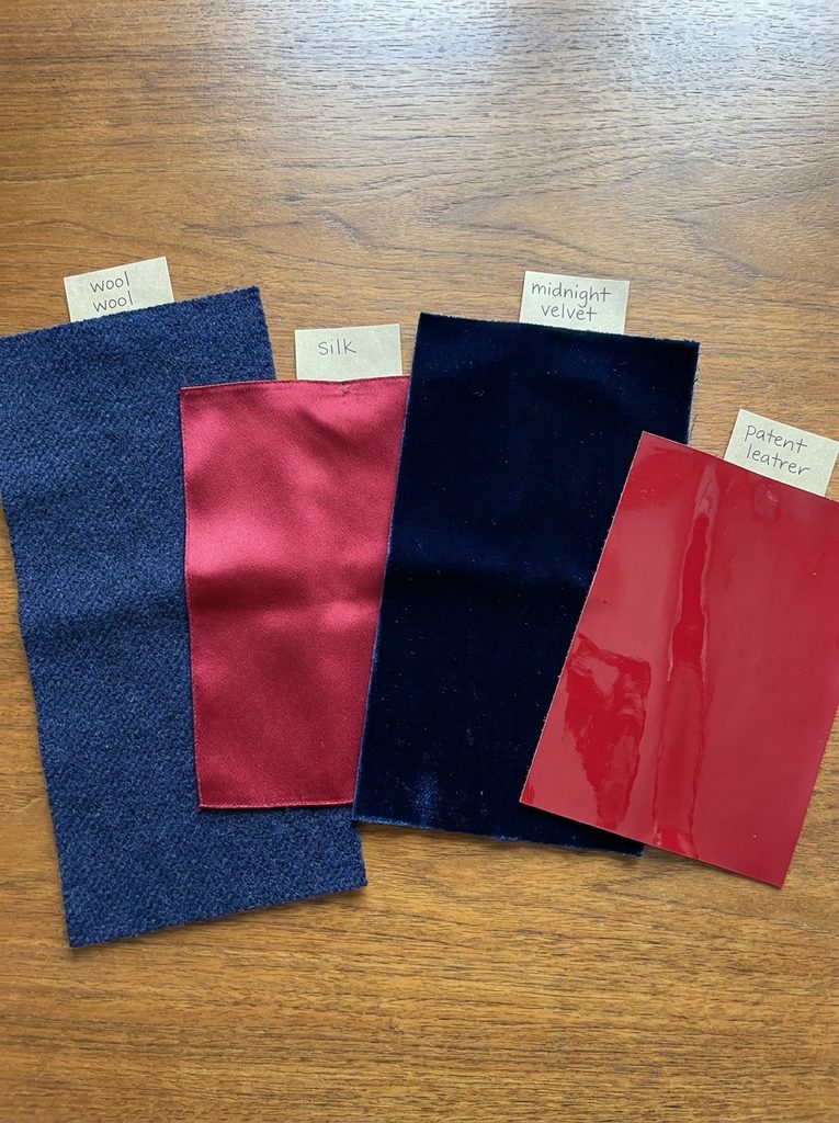 Navy wool, red silk, midnight velvet, and red patent leather fabric swatches