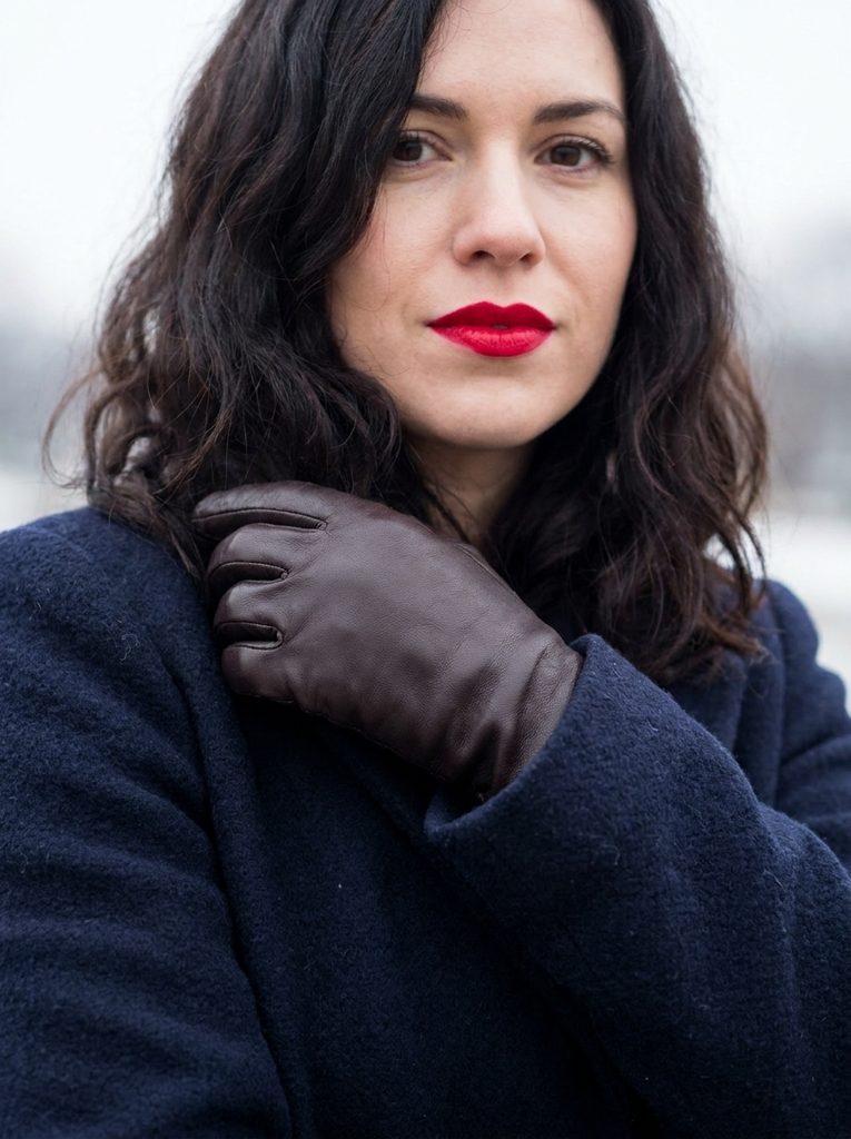 wearing woman Cherry red lipstick and leather glove held against a navy wool sleeve