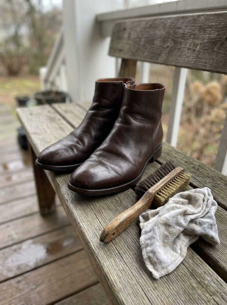 Slim leather ankle boots drying on a bench with a suede brush and cloth