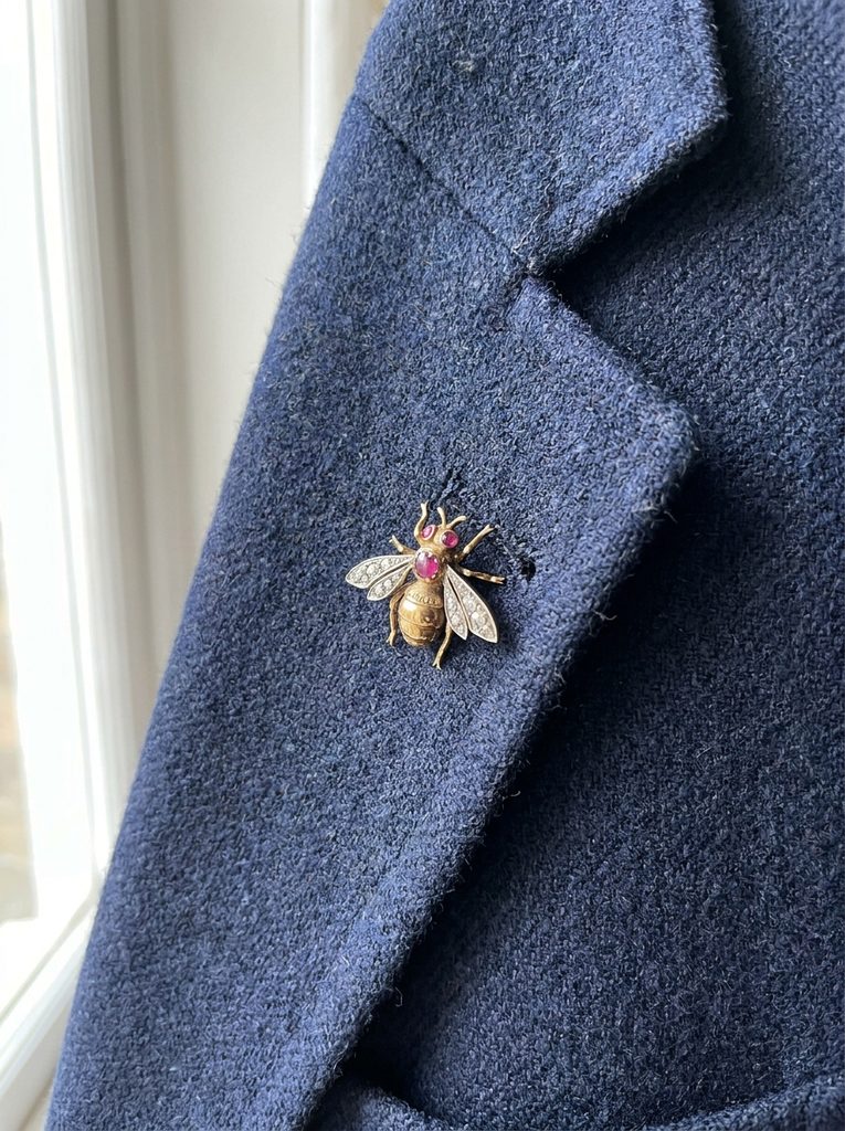 Small gold brooch pinned on the lapel of a navy wool blazer